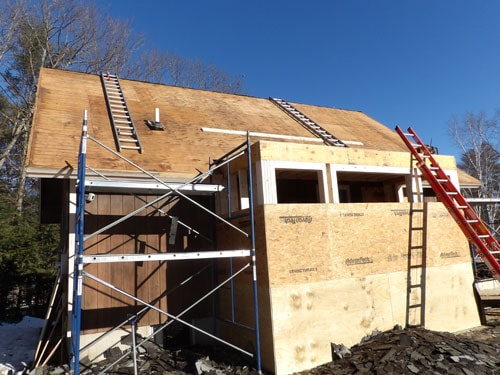 Home addition framing with scaffolding and roof sheathing in progress