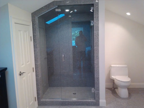 Custom bathroom with large granite tile shower enclosure and glass door