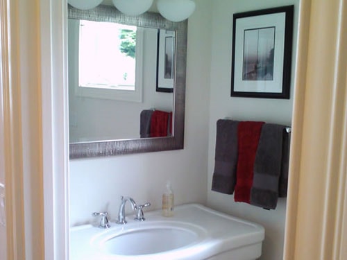 Renovated half bath with pedestal sink, framed mirror, and fresh paint