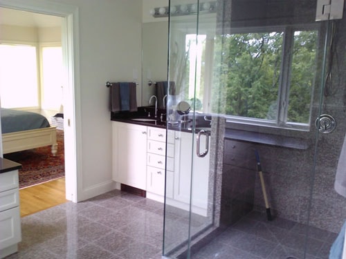 Master bath remodel with granite tile shower, white vanity, and hardwood floors