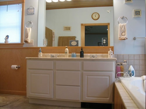 Bathroom with double vanity, large mirror, and tile surround jetted tub