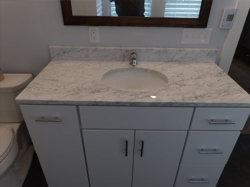 Bathroom vanity with white cabinets and marble countertop
