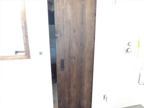 Bathroom with custom barn door, wood-framed mirror, and tile floor