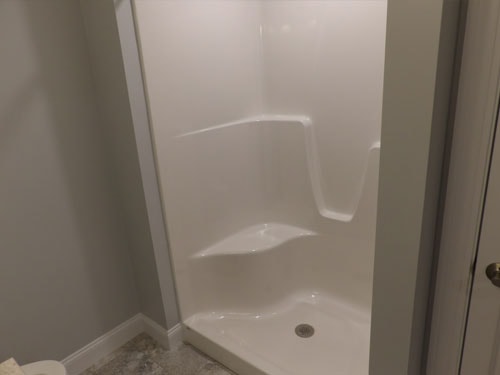 New fiberglass shower stall installation with gray tile floor
