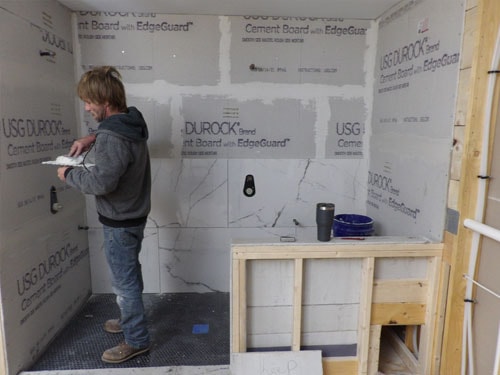 Contractor installing Durock cement board in shower enclosure with built-in niche framing