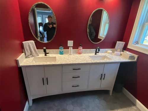 Rustic bathroom remodel with exposed wood beam ceiling, dark vanity, granite countertop, and glass shower