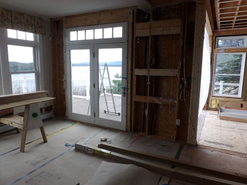 Interior renovation with French doors opening to lakeside deck, framing and rough-in work in progress