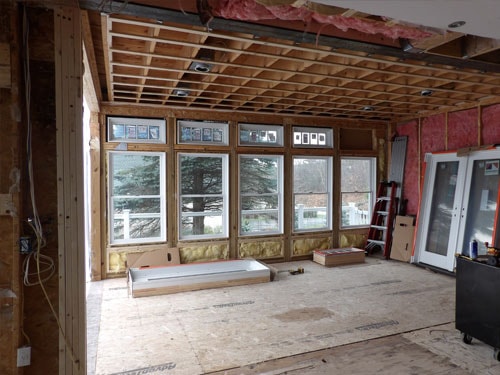 Interior addition framing with large window bank, pink insulation, and OSB subfloor