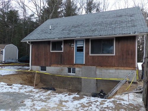 Residential exterior with new foundation excavation and concrete block work in winter