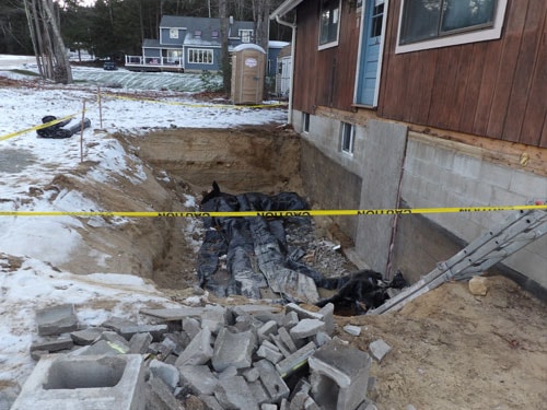 Foundation excavation with concrete block walls and drainage work in winter conditions