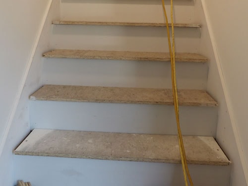 New stair treads installed with yellow extension cord during interior finish work