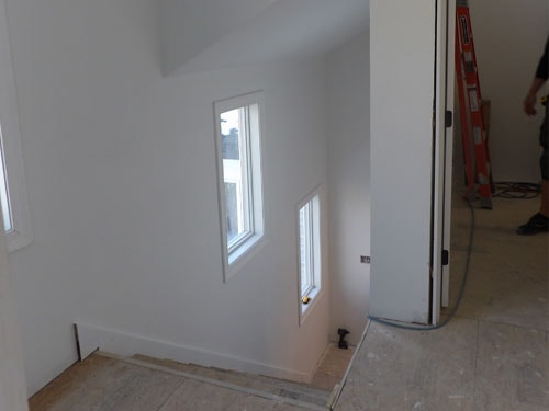Interior finish work with freshly drywalled walls, vertical windows, and open doorway