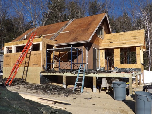 New home construction exterior framing with OSB sheathing, roof shingles, and scaffolding in winter