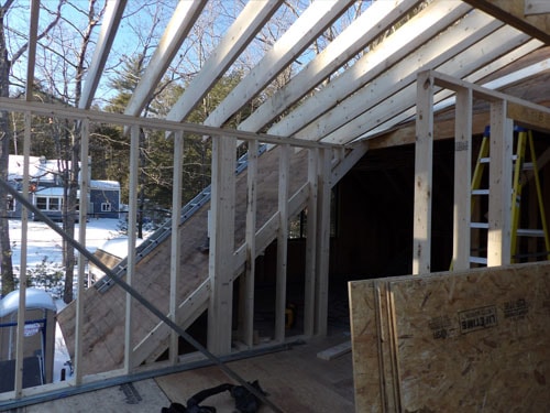 Addition framing with open roof structure and lake view through window opening in winter