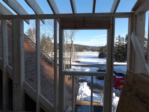 Lakeside addition framing with frozen lake view through open window opening in winter