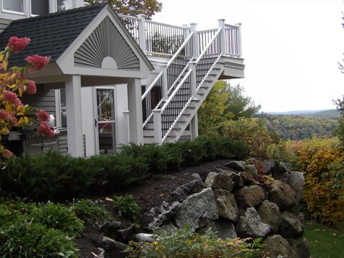 Elevated deck with white railings, black balusters, and sweeping hillside and valley views in fall foliage