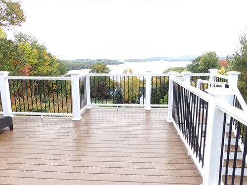 Elevated composite deck with white and black railing system overlooking lake and fall foliage