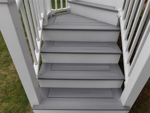 Close-up of gray composite deck stair treads with white vinyl railings and balusters