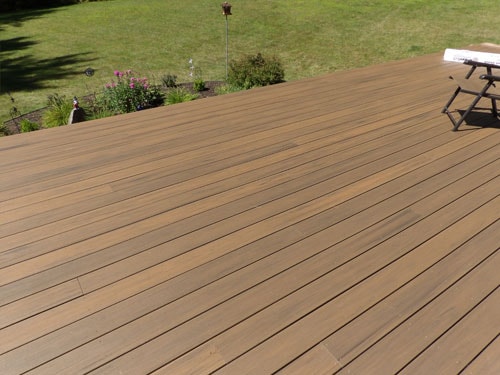 Finished warm-toned TimberTech composite deck surface with garden views and summer lawn