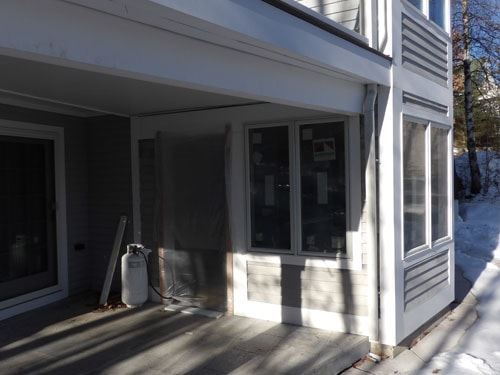 Exterior of gray home with new sliding doors and composite deck boards installed in winter