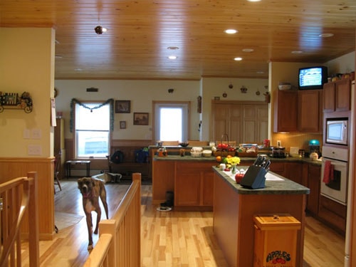 Open kitchen with knotty pine ceiling, recessed lighting, granite island countertop, maple hardwood flooring, and oak railing at stair opening