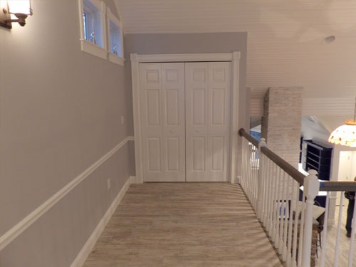 Upper hallway with six-panel double closet doors, beadboard ceiling, recessed lighting, wall sconce, and oak railing at stair opening