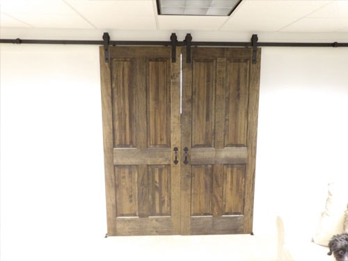 Custom double barn doors with dark walnut stain and black sliding hardware — closed position, slightly different angle showing hardware detail