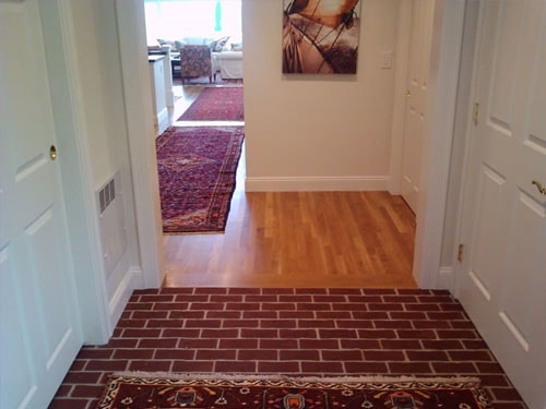 Entryway with classic brick tile floor transitioning to hardwood with Persian runner rugs