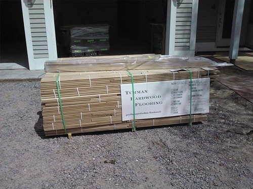 Bundle of Turman Hardwood Flooring materials wrapped and staged on driveway for delivery