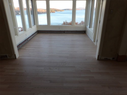 Unfinished white oak hardwood floor in sunroom with panoramic lake and fall foliage views through large windows