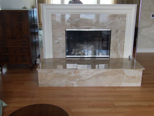 Travertine marble fireplace surround with white mantel and natural oak hardwood floor in formal living room