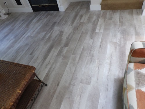 Driftwood gray LVP luxury vinyl plank floor from second angle showing wicker coffee table and sofa