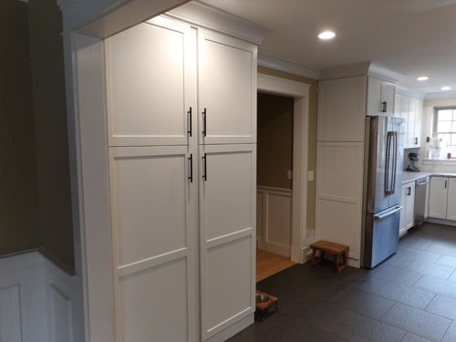 Custom white pantry cabinets with black hardware and slate tile floor