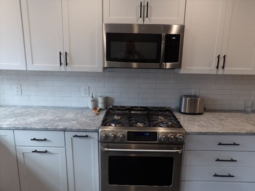 Gas range with subway tile backsplash and quartz countertops