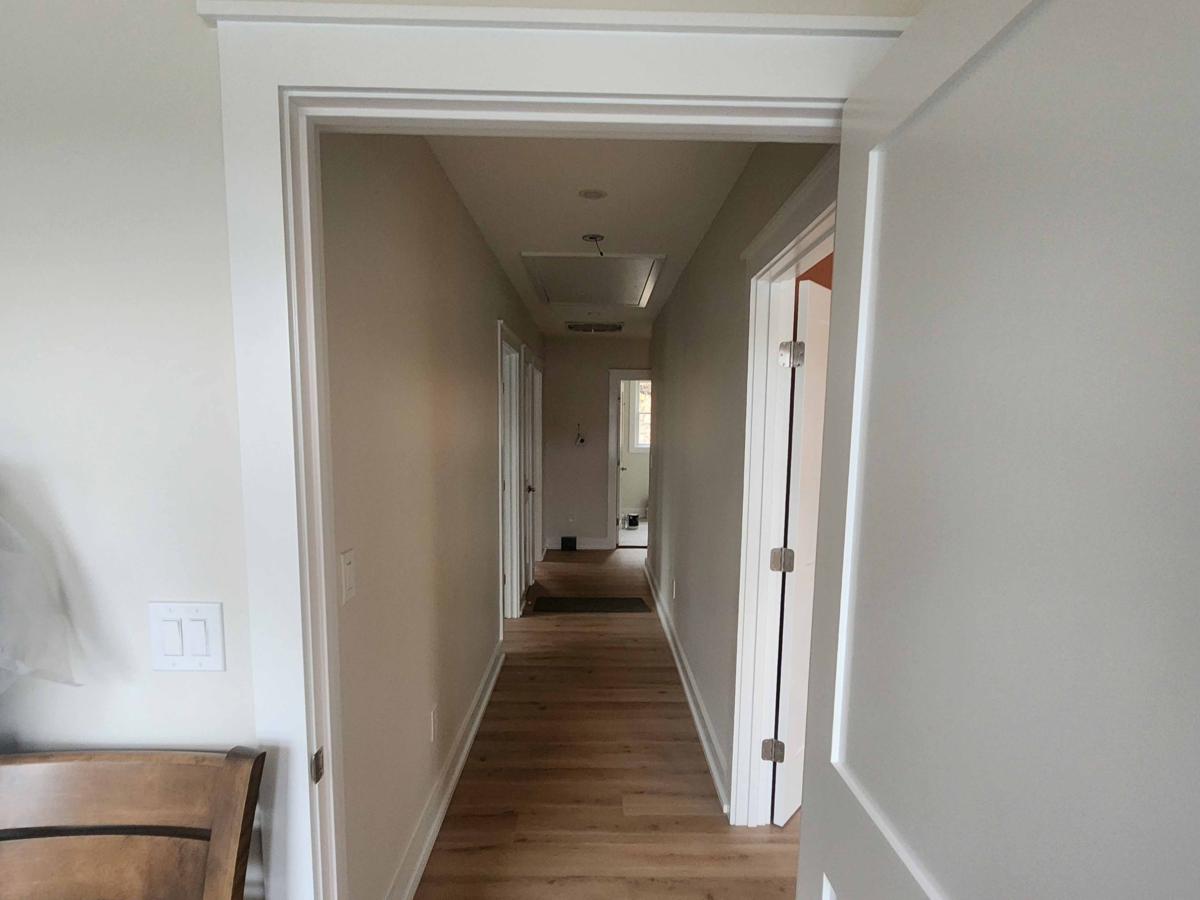Finished interior hallway with crown molding, white panel doors, and hardwood flooring
