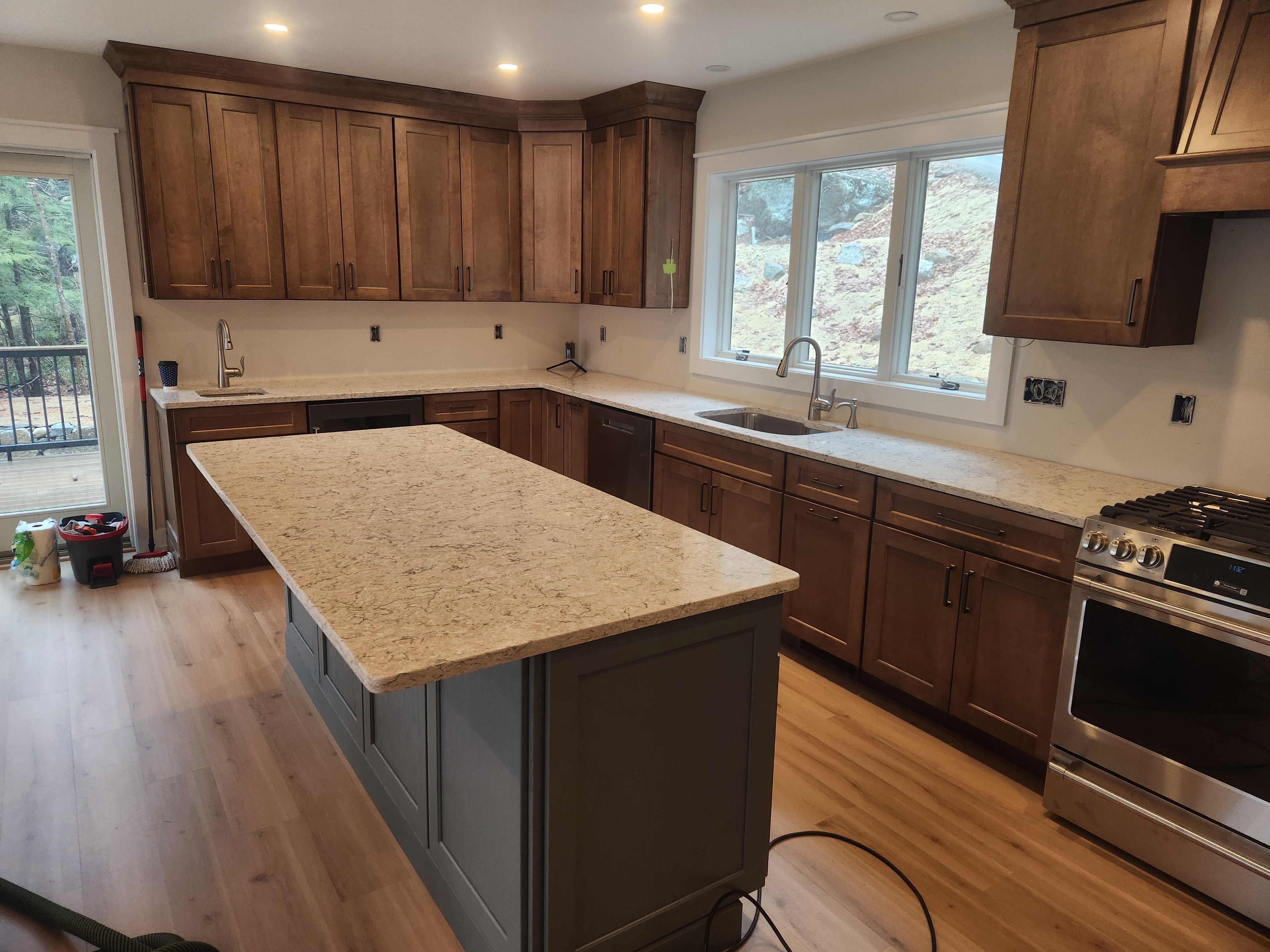 New construction kitchen from second angle showing granite island, walnut cabinets, and gas range