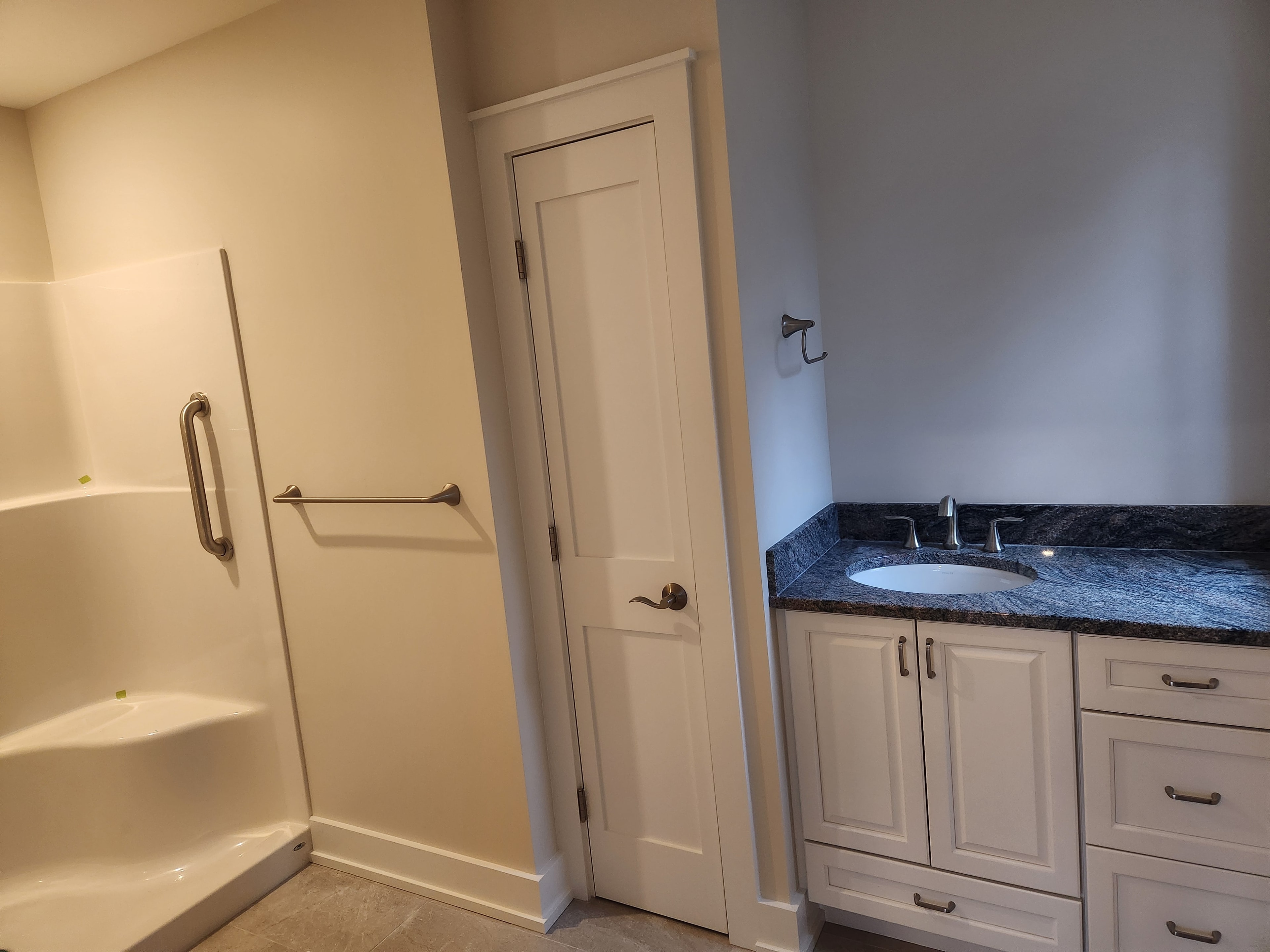 Finished bathroom with white walk-in shower, blue granite vanity, and white shaker cabinets
