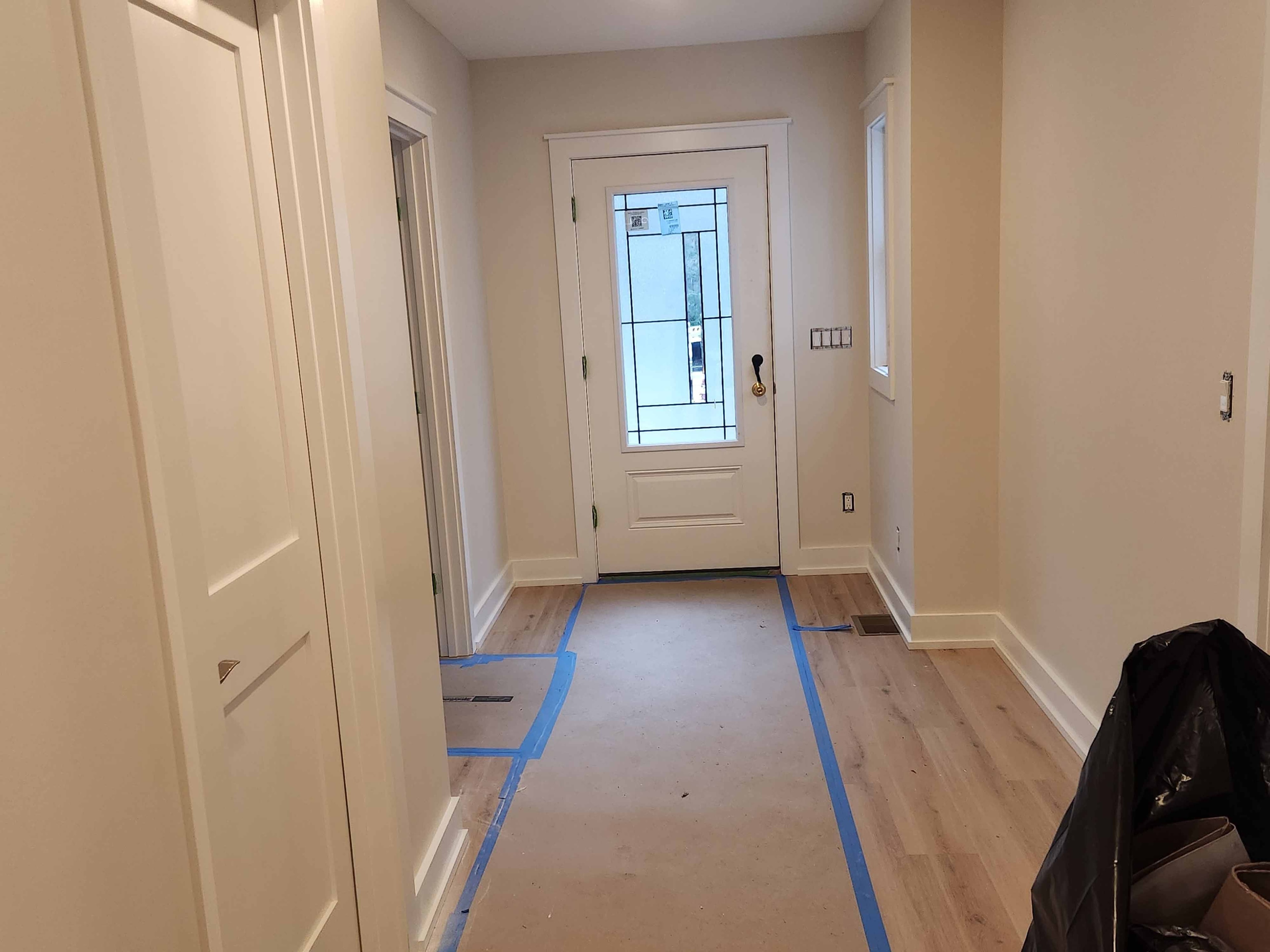New construction foyer with leaded glass entry door, LVP flooring, and white trim under final finishing