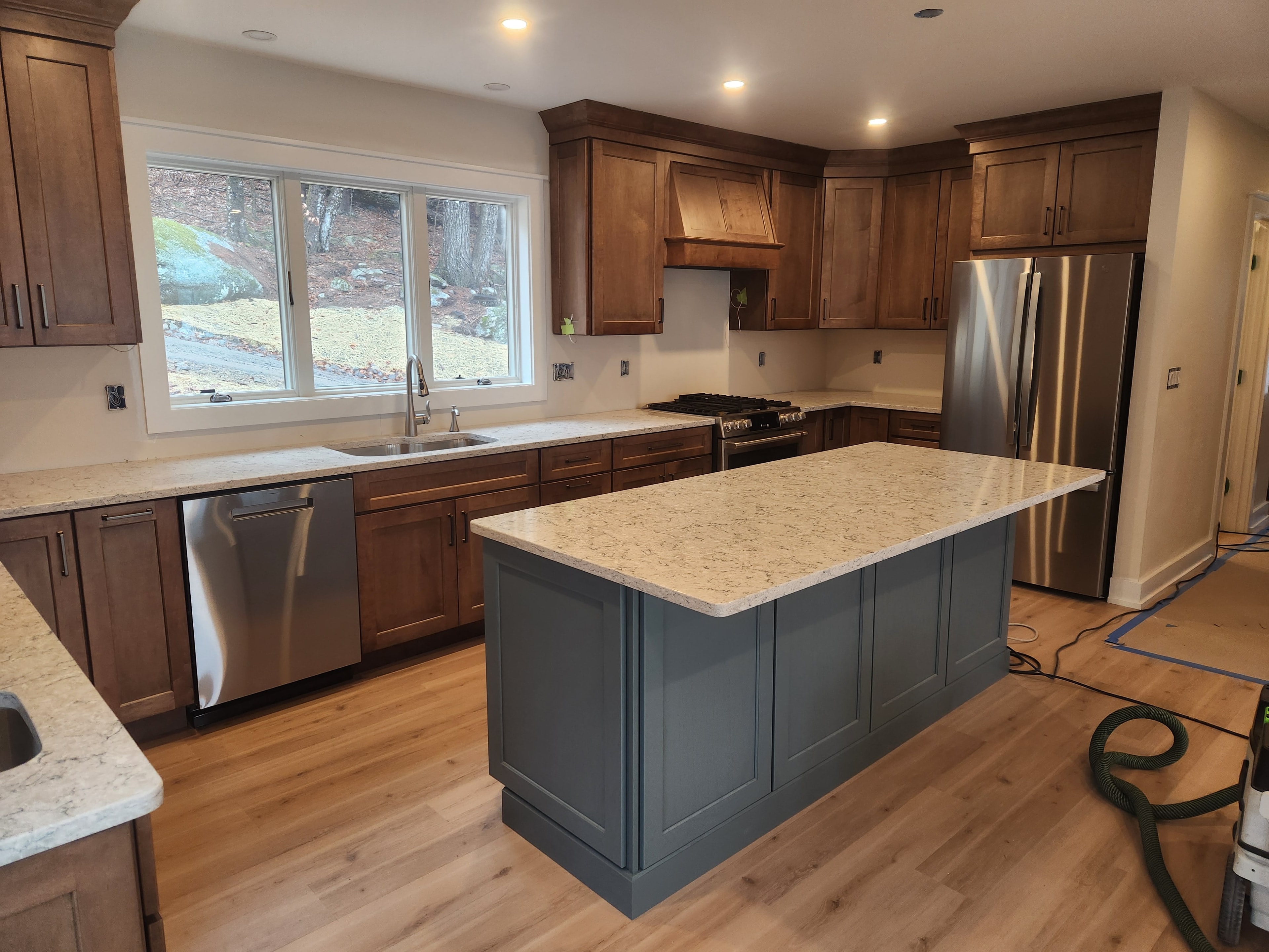 New construction kitchen near completion with walnut shaker cabinets, blue island, granite countertops, and stainless appliances