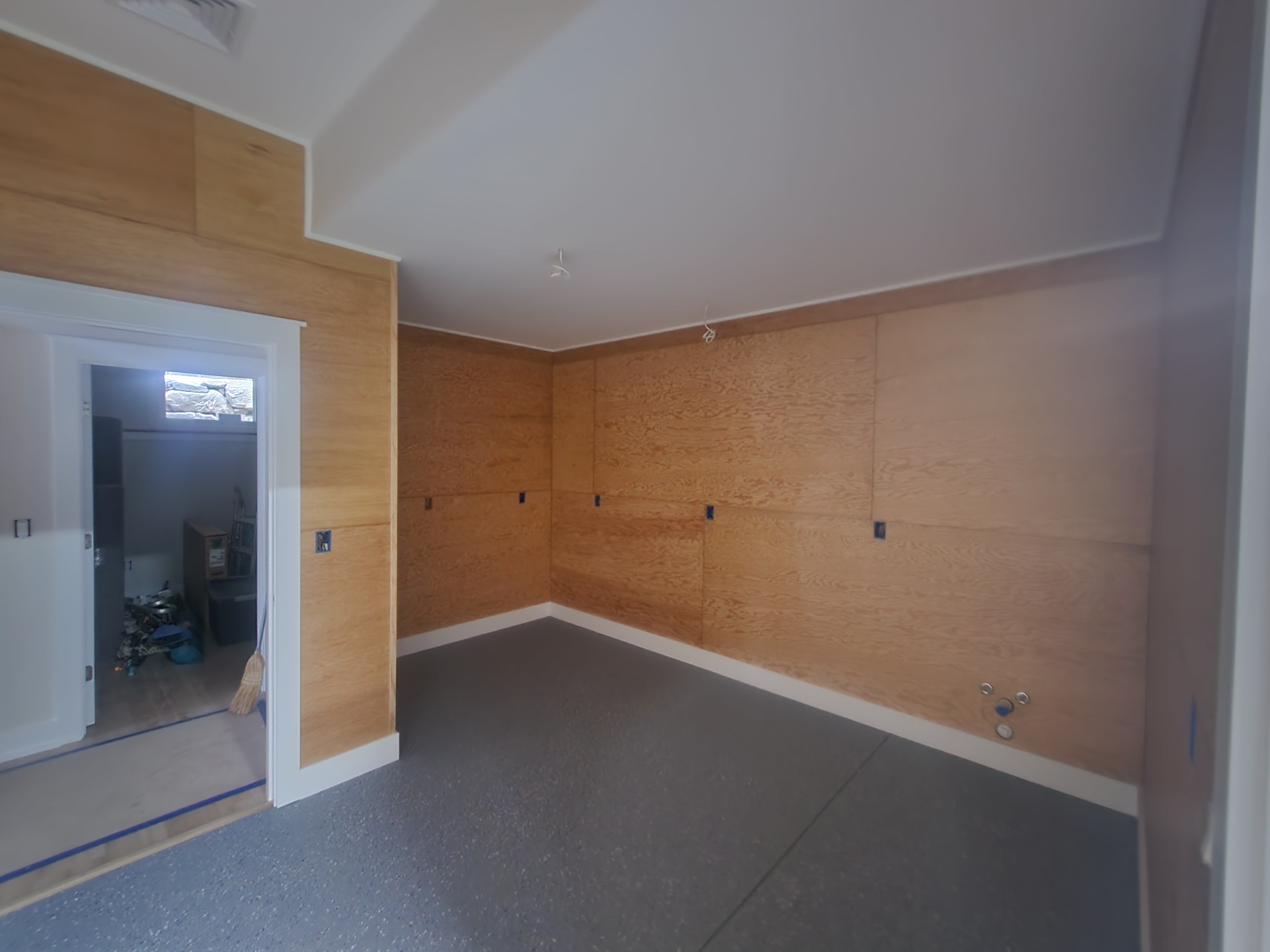 New construction garage or workshop room with OSB wall panels, epoxy chip floor, and vaulted ceiling