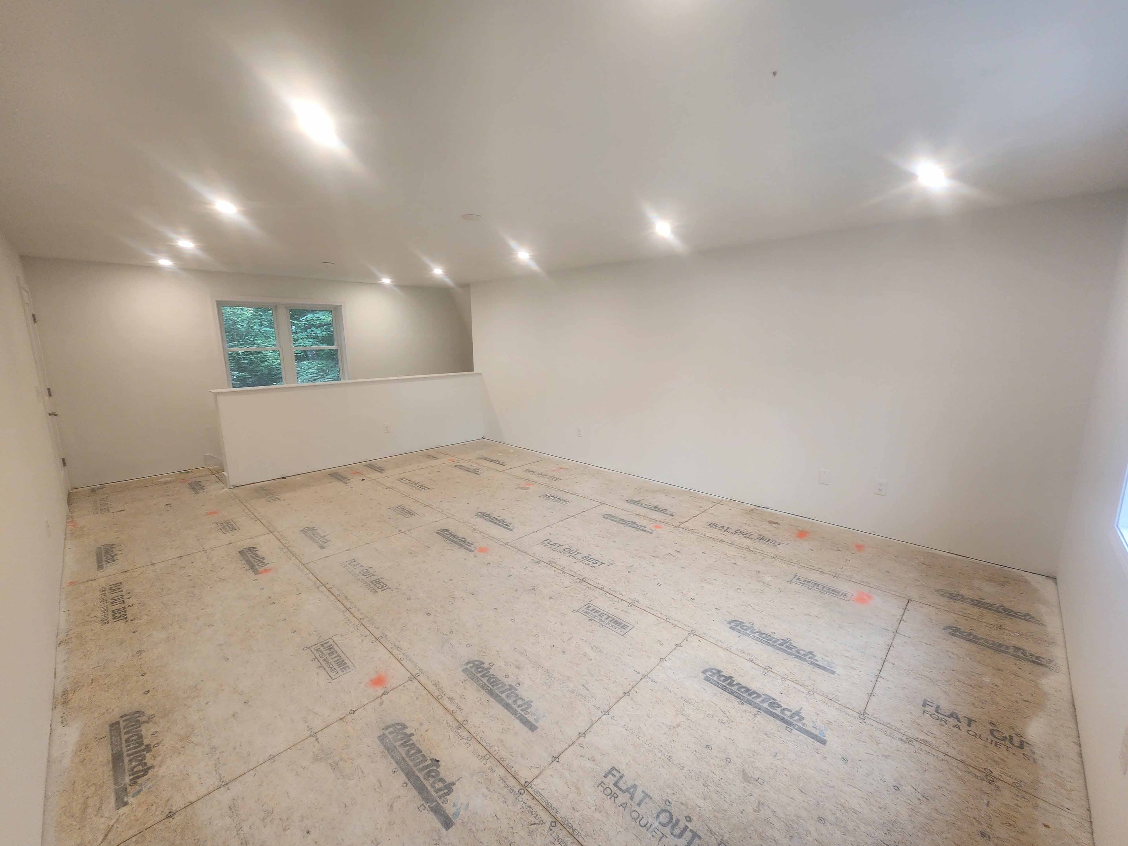 Large new construction room with recessed lighting, drywalled walls, and Advantech subfloor awaiting finish flooring