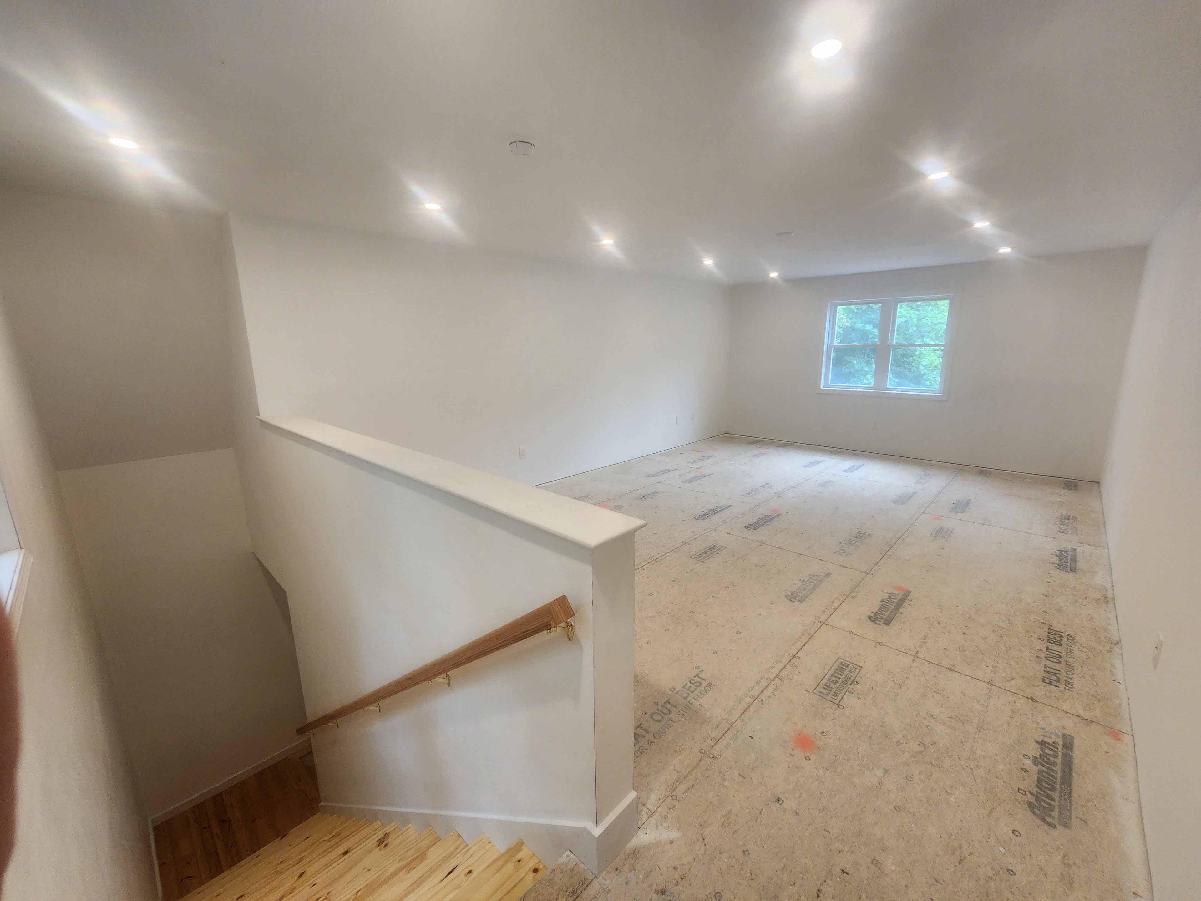 Open upper room with recessed lighting, pine staircase with wood handrail, and Advantech subfloor ready for finish flooring